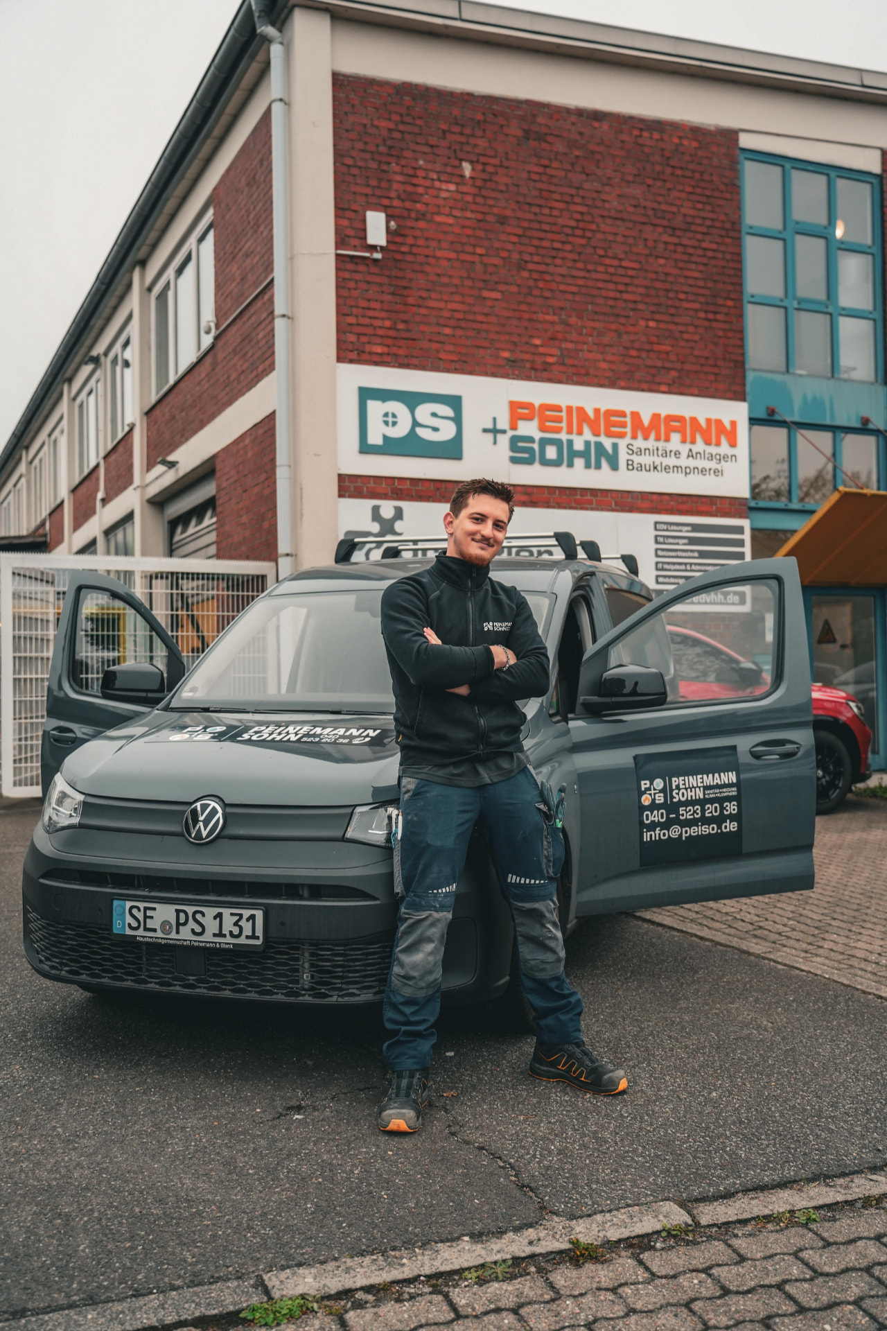 Heiz-/Regelungstechniker von Peinemann + Sohn vor dem Firmenfahrzeug